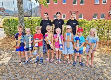 Mit ihren selbst gebauten Regenmachern zeigen die neun Kinder, was an diesem Nachmittag entstanden ist; der Musikverein gab ihnen außerdem Gelegenheit, weitere Instrumente auszuprobieren.